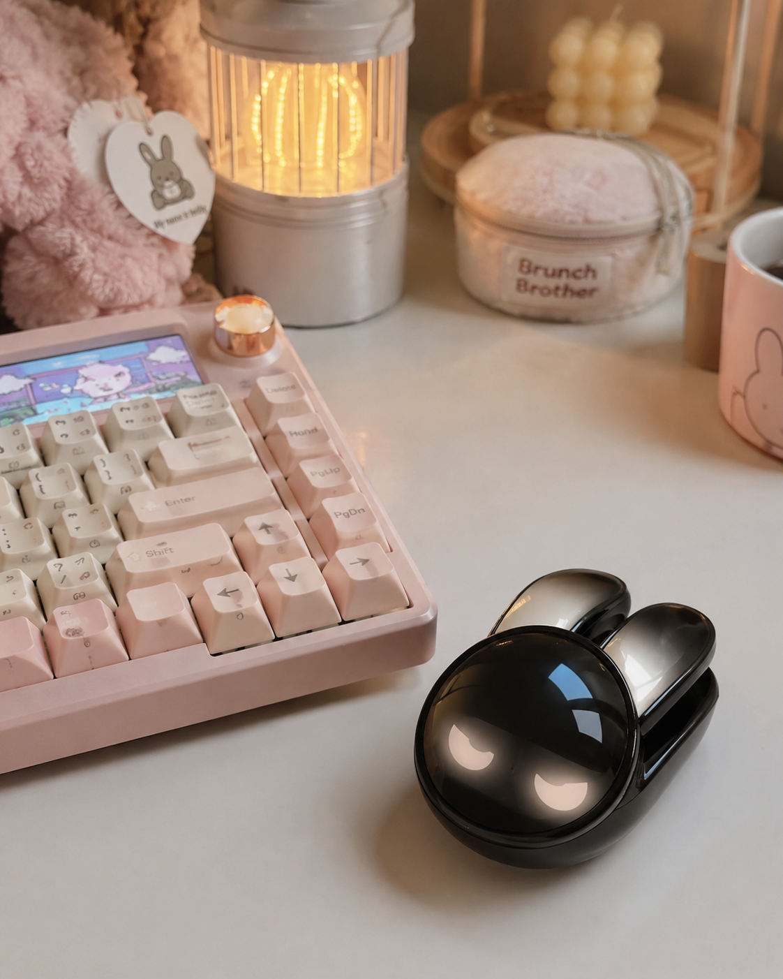 Black rabbit-shaped wireless mouse with white glowing eyes next to a pink mechanical keyboard