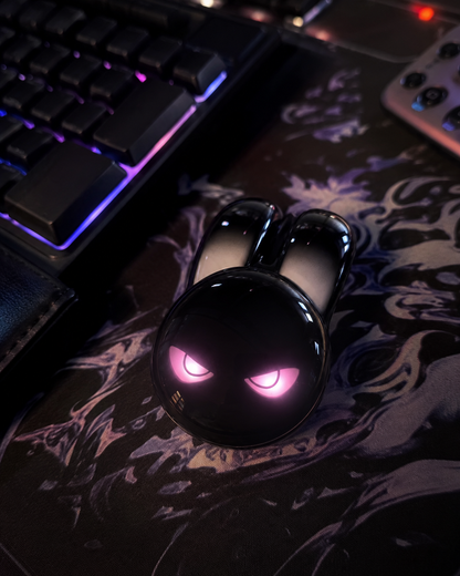 Black evil bunny wireless mouse with glowing pink eyes on a dark floral desk mat